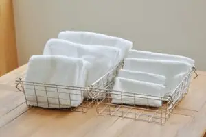 一般的なタオルと、薄くたたまれたKajimoreのタオルが、それぞれワイヤーバスケットにきれいに収納されている画像。
