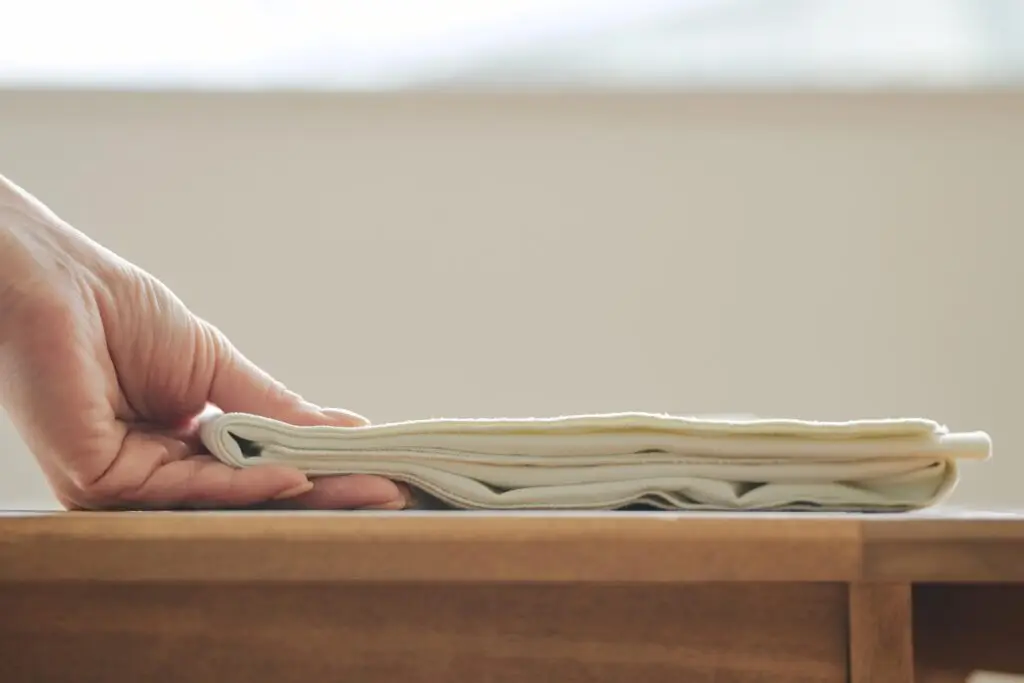 Kajimoreのアイボリーのタオルが、指でつまむことができるほど薄く、コンパクトに折りたたまれている画像。