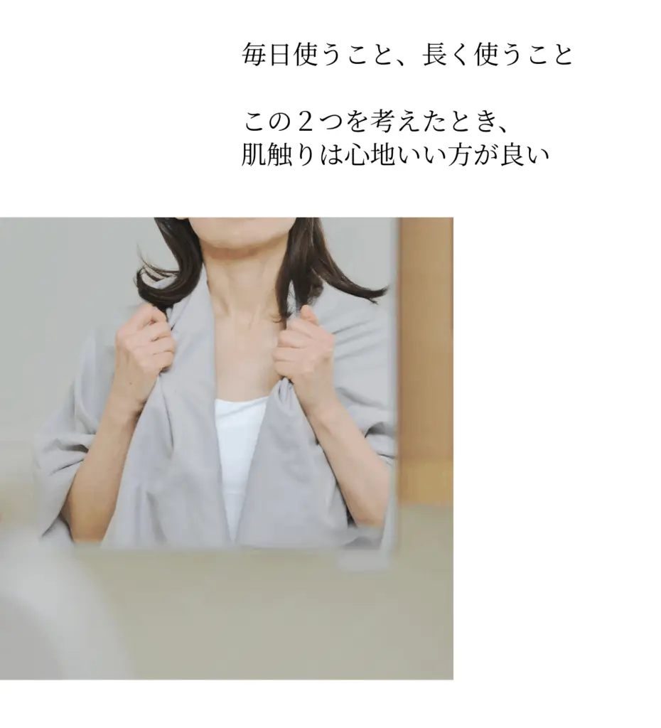 女性がKajimoreの薄いグレーのタオル（またはバスローブ）を体に当てている画像。毎日使うものだから心地よさを重視。