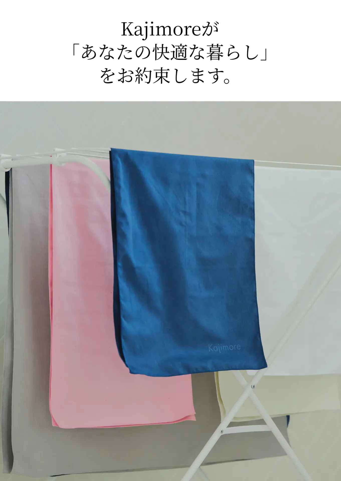 部屋干しされたKajimoreのバスタオル（グレー、ピンク、青）の画像。清潔感のある空間でKajimoreが「快適な暮らし」を約束。