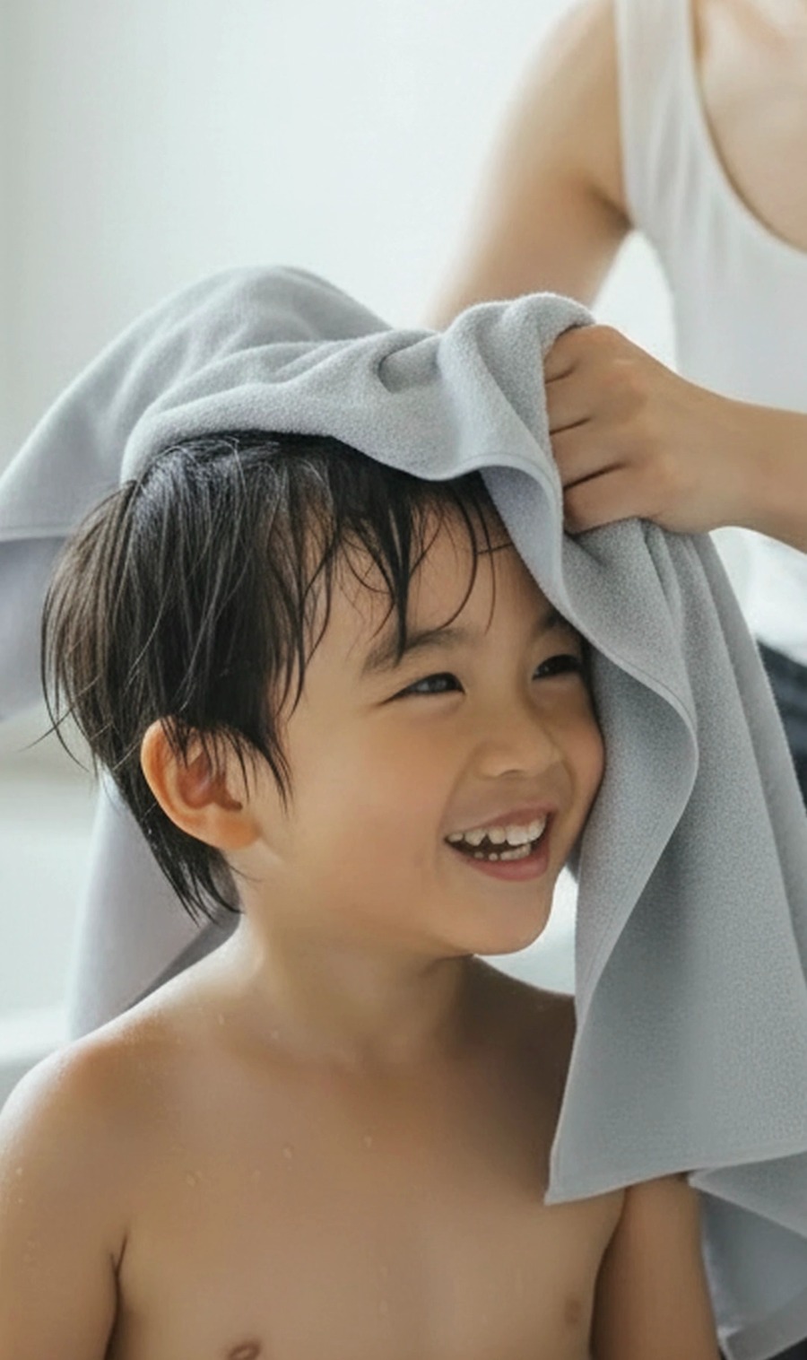 お風呂上がりに、母親が子供の髪をKajimoreのグレーのタオルで拭いている様子。