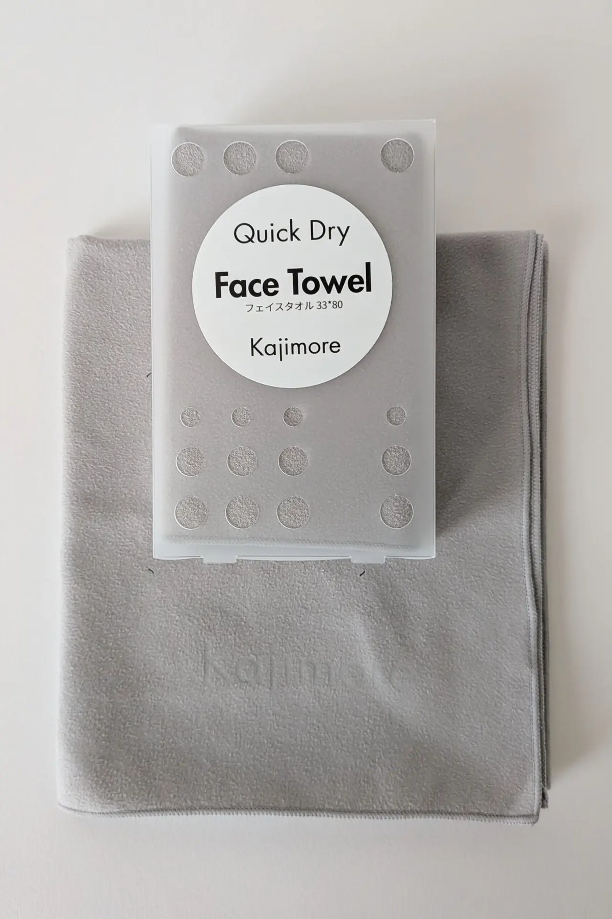 グレーのKajimoreフェイスタオルと、そのパッケージのプロダクトショット。